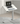 Small standing desk with a 70cm white tilting tabletop placed beside a sofa, featuring a laptop on the desk, highlighting its portable design and left/right installation flexibility