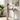 Woman using a laptop at KOWO chamfered wood top standing desk in a bright room with a plant and artwork.